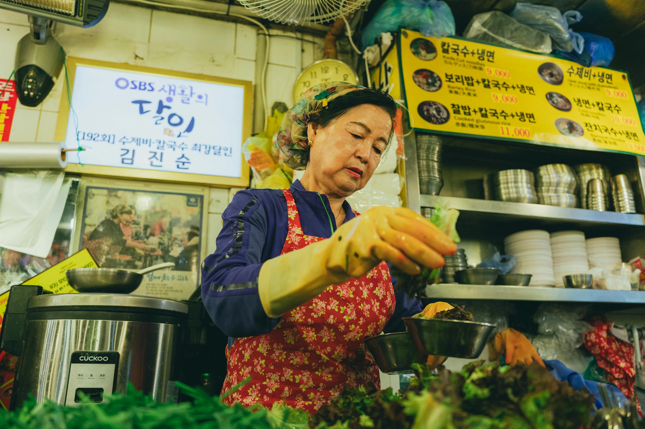 Photo by Khanh Nguyen A woman preparing food in a traditional Korean market in Seoul, showcasing vibrant culinary culture.