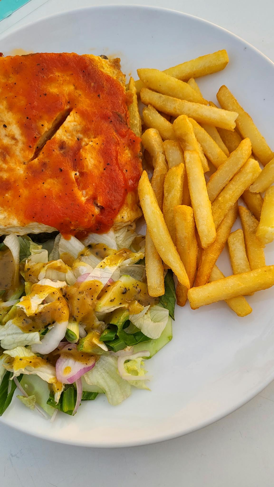 Savory lasagna paired with crispy fries and fresh salad on a plate.